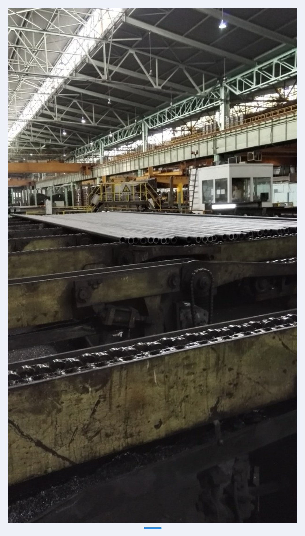 Steel pipe output line with conveyor chain in operation